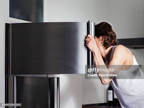 man looking in freezer, face obscured by door, side view - freezer stock-fotos und bilder