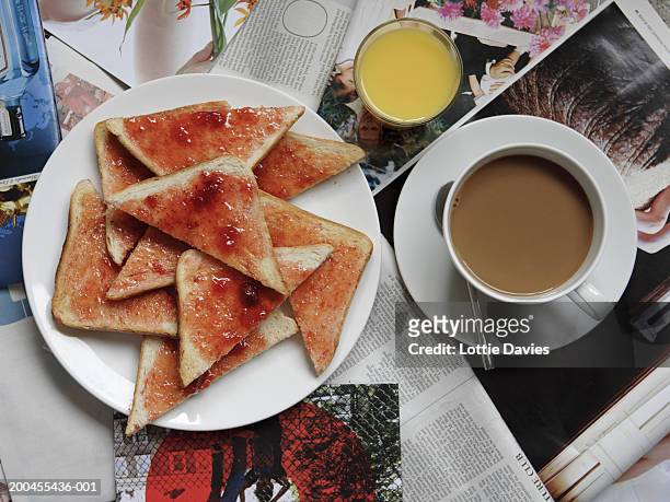 plate of toast and jam on newspapers with cup of tea and orange juice - magazine spread stock pictures, royalty-free photos & images