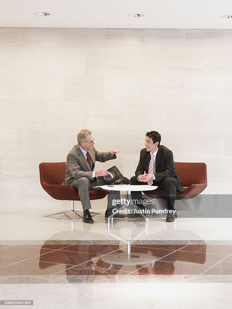 Two businessmen sitting by table talking