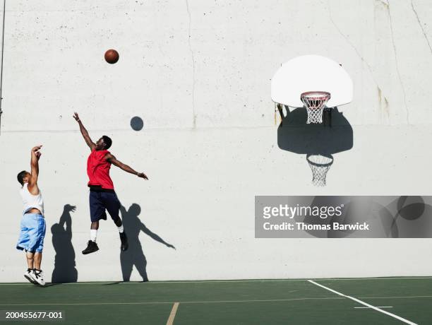 two young men playing basketball outdoors, side view - shooting baskets stock pictures, royalty-free photos & images