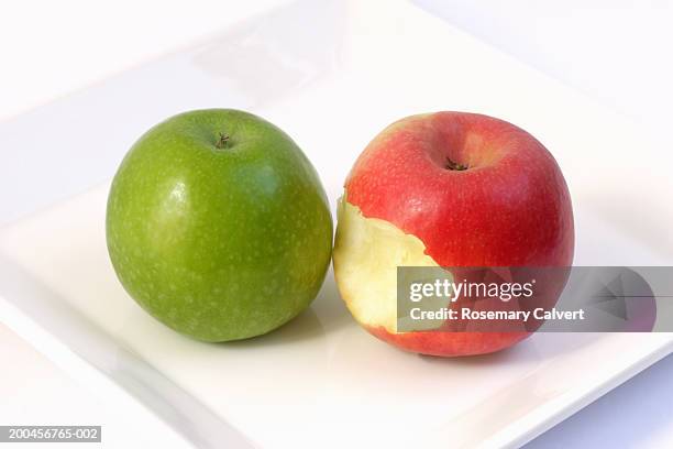 granny smith apple and pink lady apple with bite taken, on plate - lady apple stock pictures, royalty-free photos & images