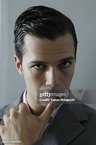 portrait of young man, thumb on chin - slicked back hair imagens e fotografias de stock