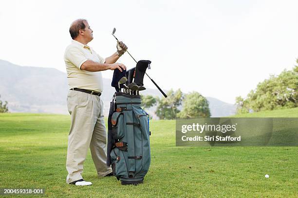mature man taking golf club from bag - golf clubs stock pictures, royalty-free photos & images