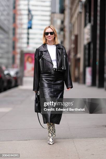 Lisa Aiken wears sunglasses, a white t-shirt, a black leather biker jacket , a black leather skirt , snake printed pattern high heels pointed leather...