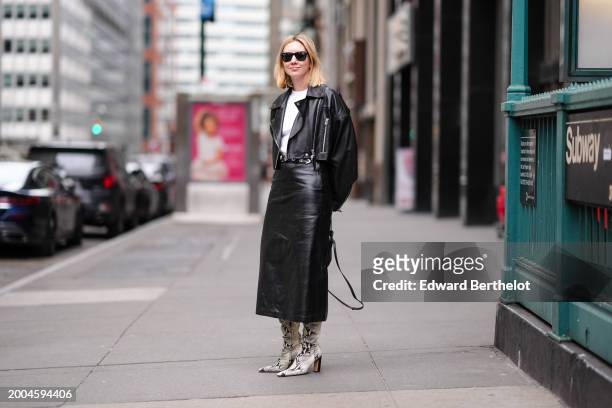 Lisa Aiken wears sunglasses, a white t-shirt, a black leather biker jacket , a black leather skirt , snake printed pattern high heels pointed leather...