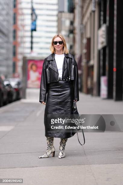 Lisa Aiken wears sunglasses, a white t-shirt, a black leather biker jacket , a black leather skirt , snake printed pattern high heels pointed leather...