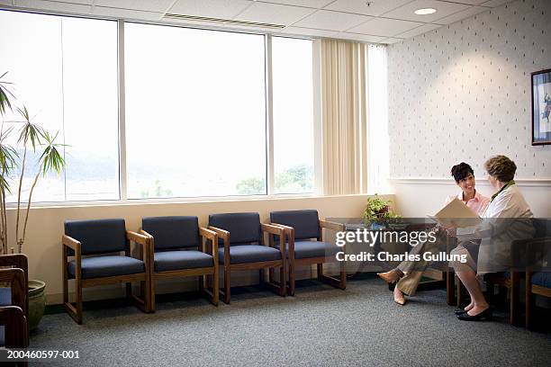 woman sitting with doctor in doctor's waiting room, talking - waiting room - fotografias e filmes do acervo