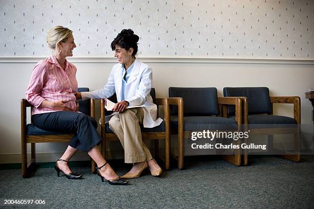 doctor feeling pregnant woman's stomach in waiting room - woman excited sitting chair stock pictures, royalty-free photos & images