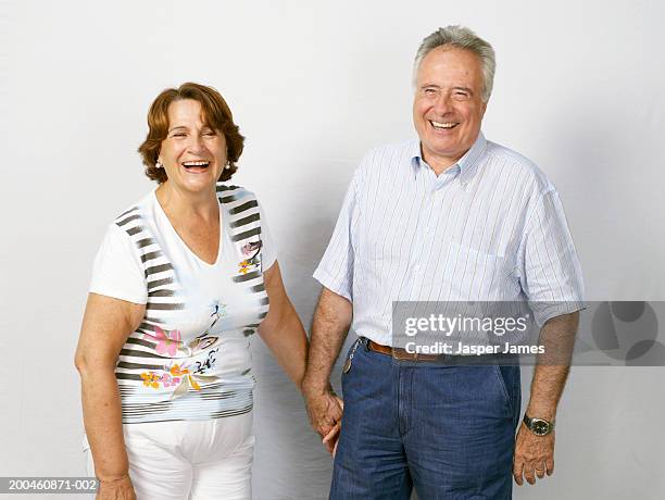 senior couple, holding hands, laughing, portrait - senioren koppel studio stockfoto's en -beelden