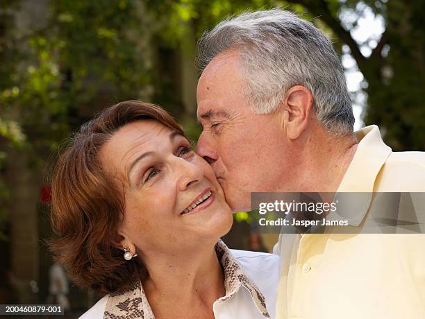 senior couple, man kissing woman on cheek - cheek kiss stock pictures, royalty-free photos & images