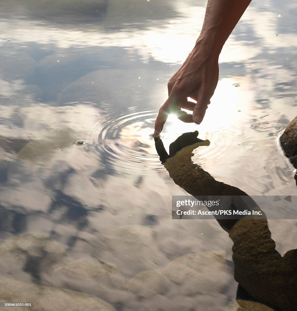 Woman touching lake surface, close-up