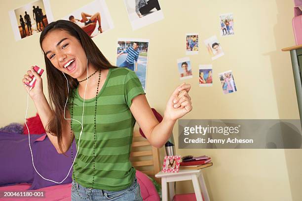 girl (13-15) dancing in bedroom, listening to earphones, smiling - girl black hair room stock pictures, royalty-free photos & images
