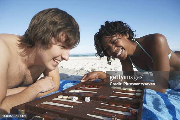 teenage couple (16-18) on beach, playing backgammon, laughing - backgammon ストックフォトと画像