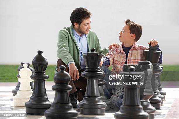 man and boy (8-10) by giant chess set - playing chess stockfoto's en -beelden