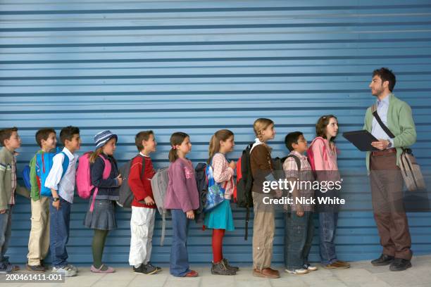 male teacher by row of children (8-12), side view - people in a row stock pictures, royalty-free photos & images