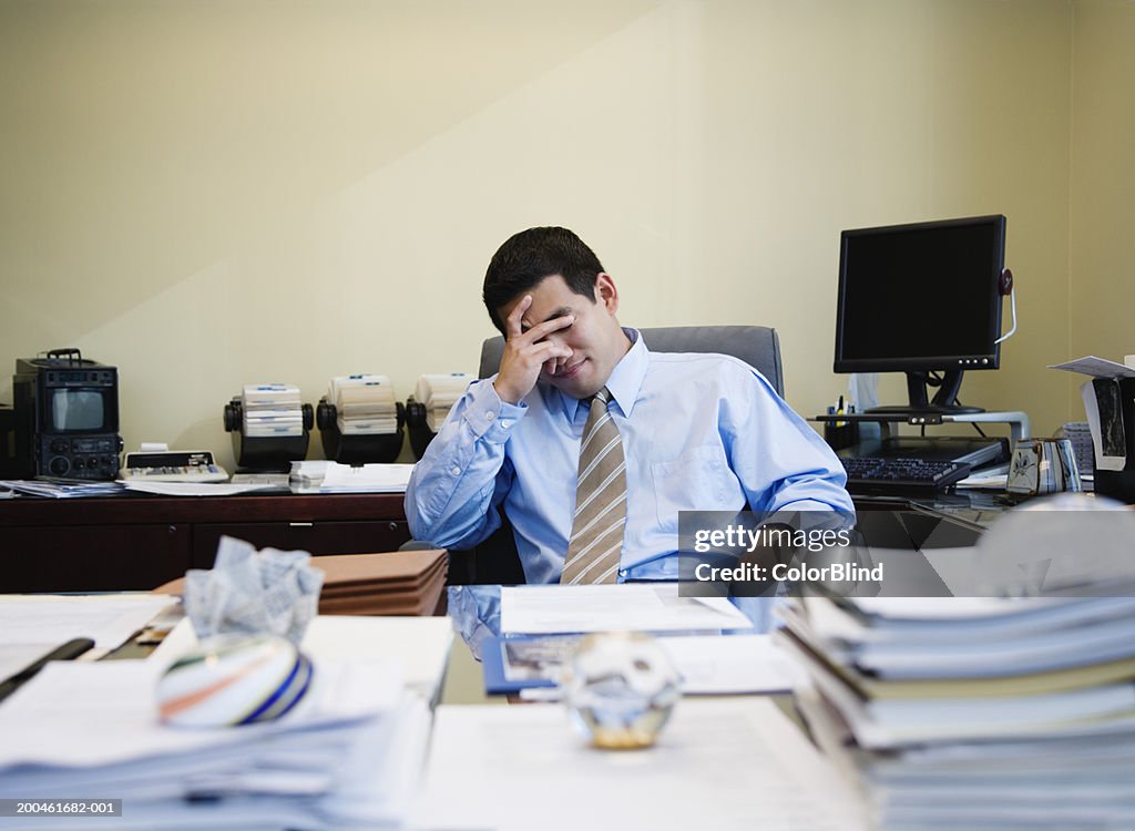 Businessman at desk with hand on head