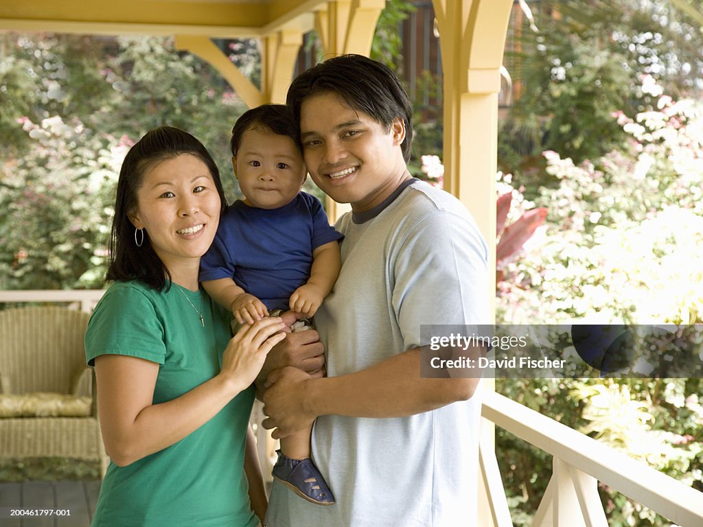 Young parents reading to two boys (1-3) on porch