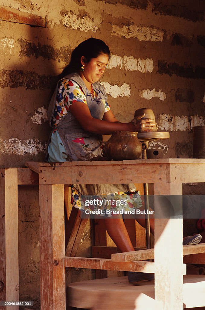 Guatemala, woman spinning pottery on wheel