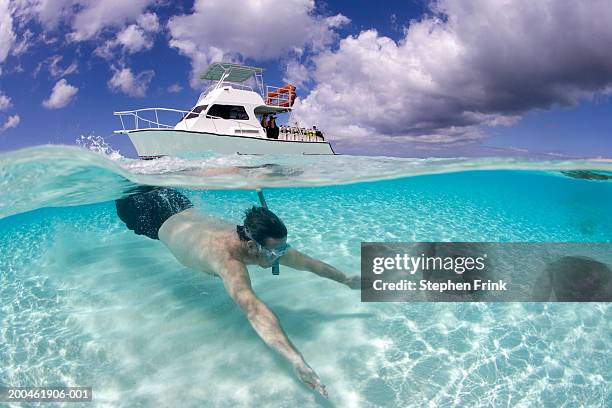 man snorkeling, dive boat in background, surface view - bermuda snorkel stock pictures, royalty-free photos & images