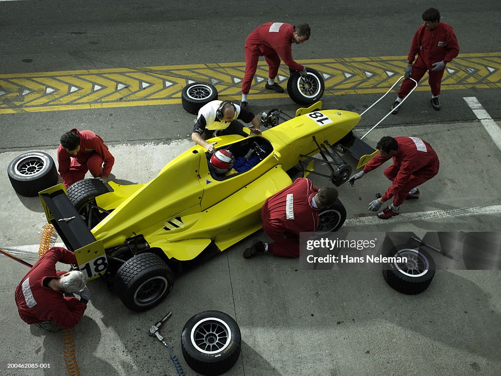 Pit crew changing tires on open-wheel single-seater racing car race car, elevated view