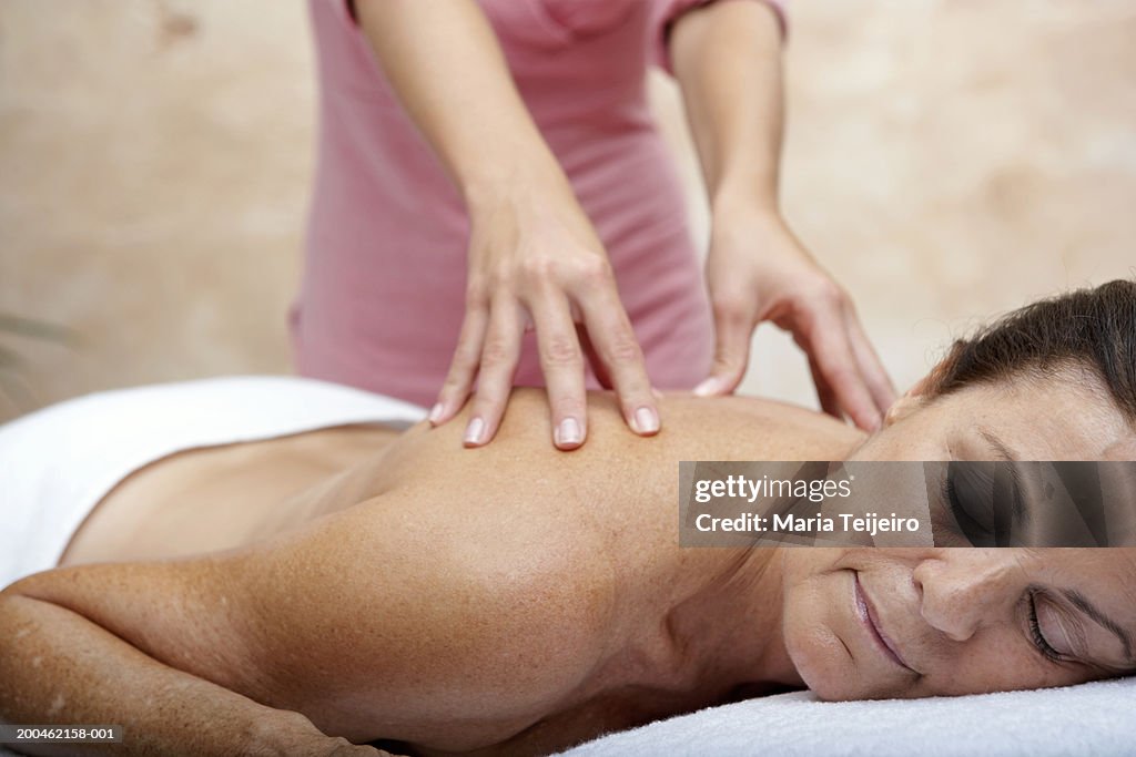 Mature woman lying on treatment table receiving massage, eyes closed