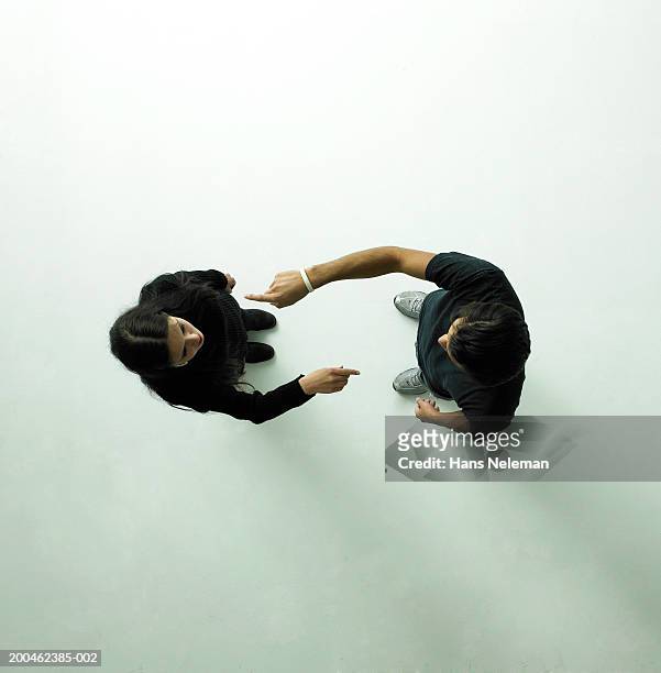 young couple pointing at each other, view from above - diverbio foto e immagini stock