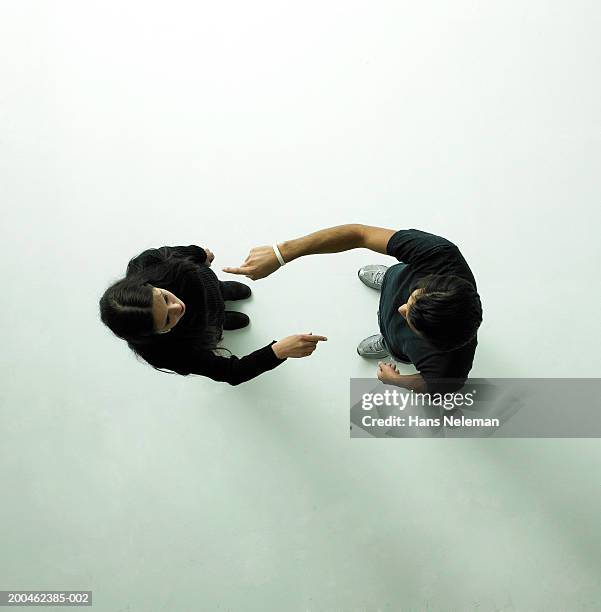 young couple pointing at each other, view from above - couple pointing imagens e fotografias de stock