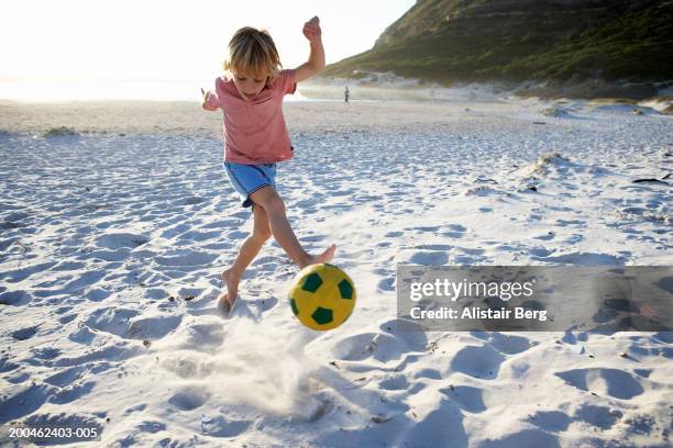 boy (4-6) kicking football on sandy beach - kids soccer stock pictures, royalty-free photos & images