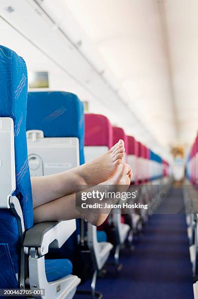 woman resting feet on seat armrest of commercial airplane - man barefoot stock-fotos und bilder