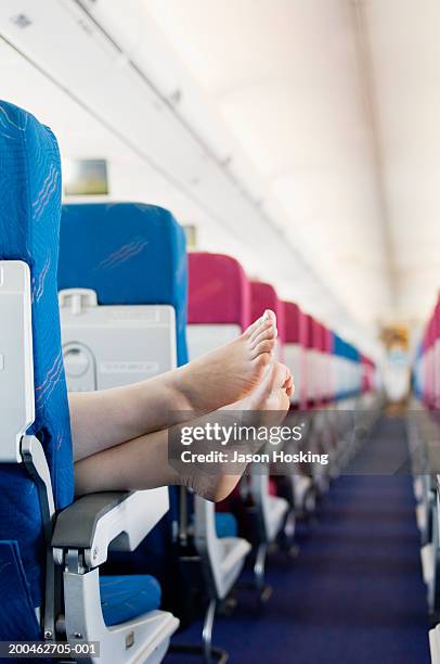 woman resting feet on seat armrest of commercial airplane - descalzo fotografías e imágenes de stock