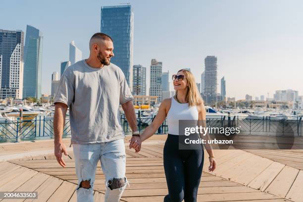 young couple holding hands while walking near souq sharq in kuwait city - alto descrição física imagens e fotografias de stock