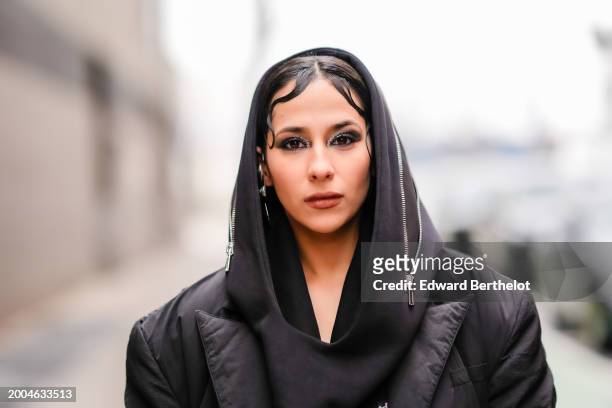 Samia Laaboudi wears Oyeleke black long puffer coat, Corinna Houidi black hood with silver zipper detail, Area silver crystal mussel flower single...