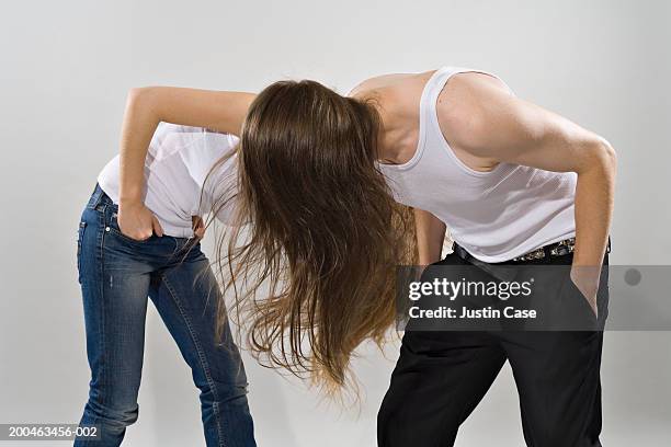 teenage girl (16-18) and young man with long hair head banging - headbanging stock pictures, royalty-free photos & images