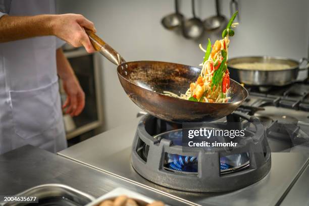 chef preparing food in restaurant kitchen - wok stockfoto's en -beelden