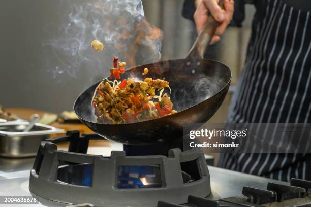 chef preparing food in restaurant kitchen - wok stockfoto's en -beelden