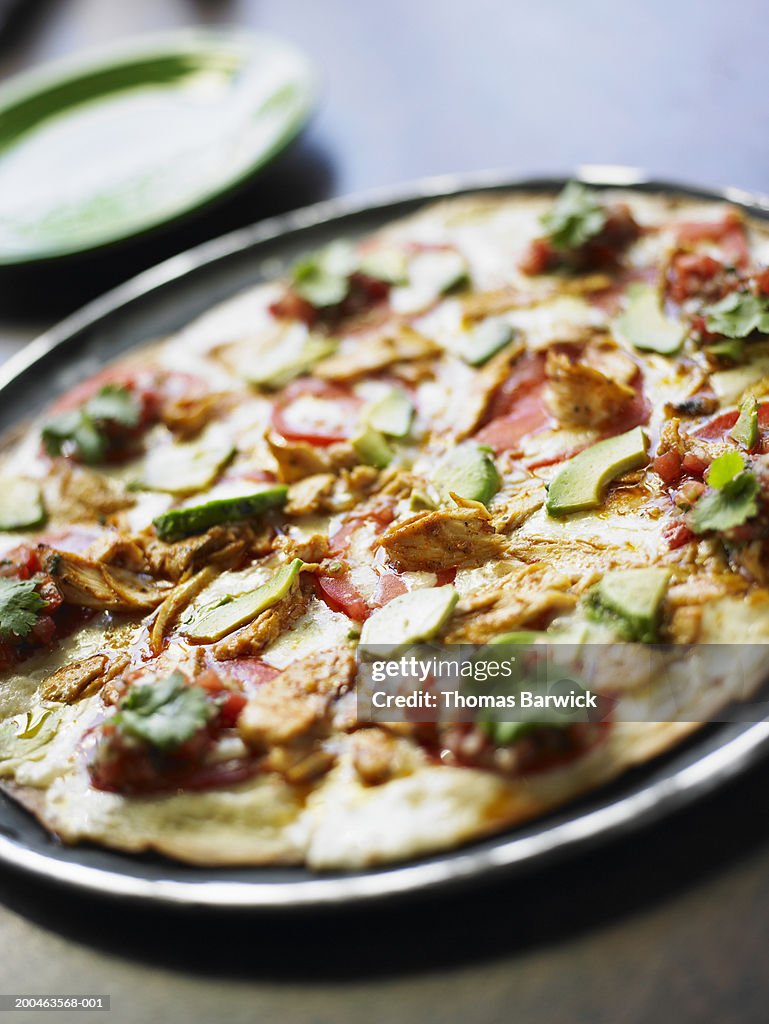 Southwest style pizza with chicken, tomatoes, cilantro and avocado
