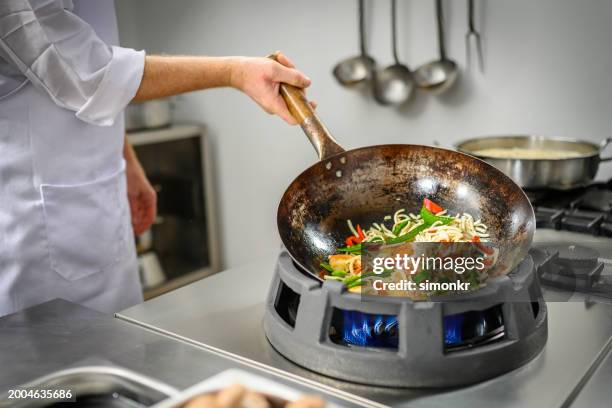 chef preparing food in restaurant kitchen - chef tossing fire stock-fotos und bilder