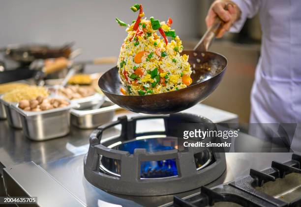 chef cooking vegetables and rice with scrambled eggs in pan - chef tossing fire stock-fotos und bilder
