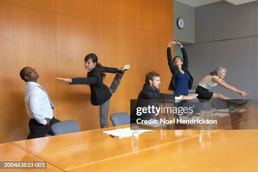 Executives in conference room stretching Executives in conference room stretching