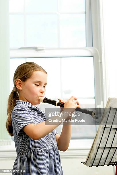 girl (6-8) playing recorder and reading music - blockflöte stock-fotos und bilder