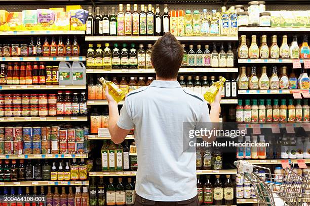 young man looking at bottles of oil in market, rear view, close-up - alternative viewpoint stock pictures, royalty-free photos & images