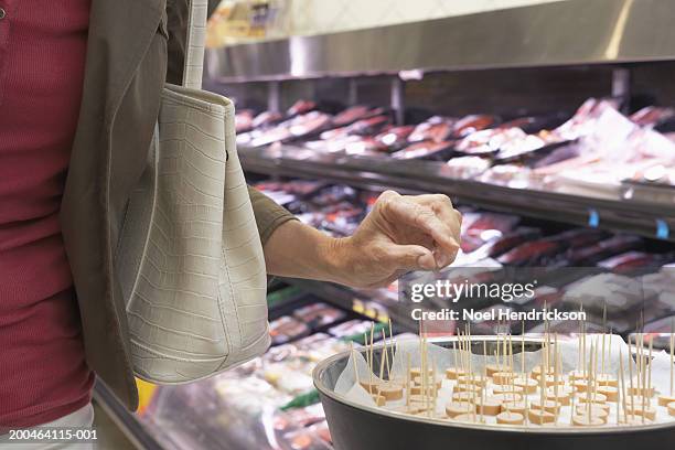 mujer madura teniendo muestra en supermercado, sección media, primer plano - sabor fotografías e imágenes de stock