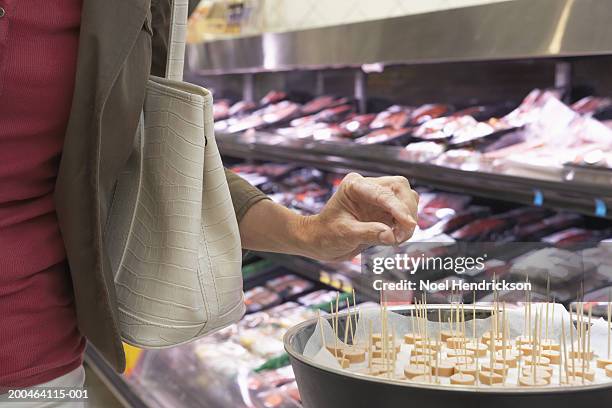 mature woman taking sample in supermarket, mid section, close-up - taste stock pictures, royalty-free photos & images