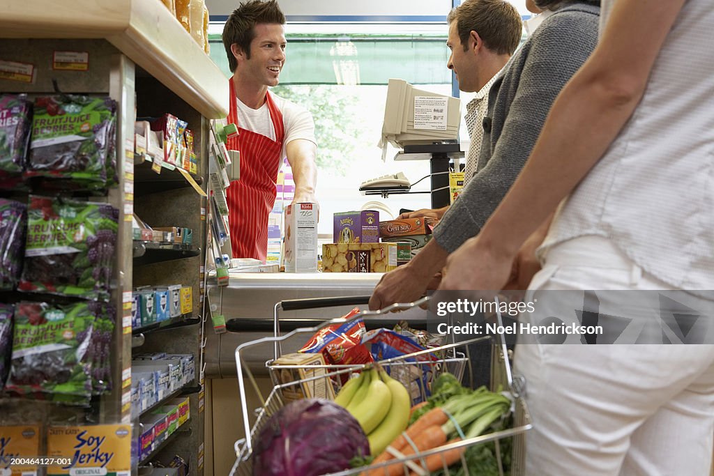 Cashier smiling at customer on checkout line in supermarket, close-up