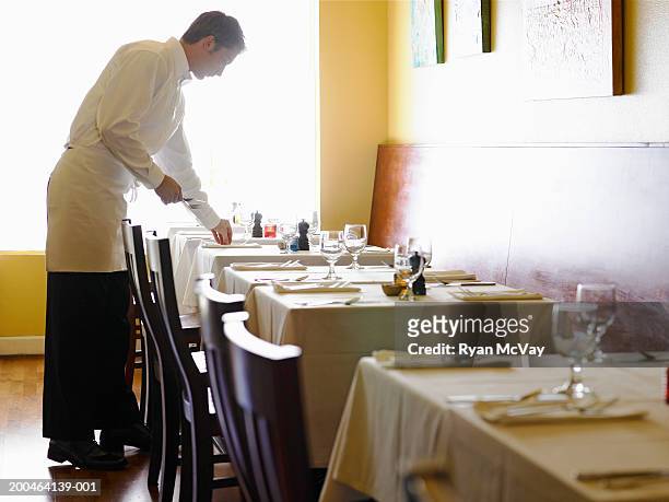 young man setting tables in restaurant, side view - luxury table setting stock pictures, royalty-free photos & images