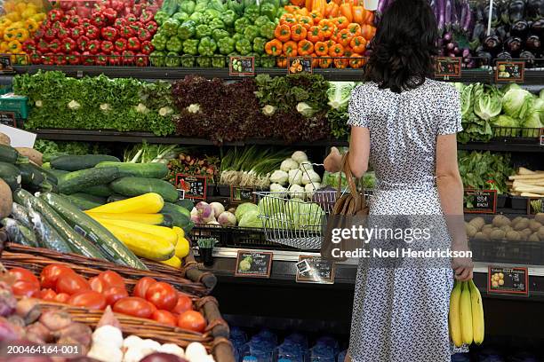 woman holding bananas in produce aisle of supermarket, rear view - produce aisle photos et images de collection