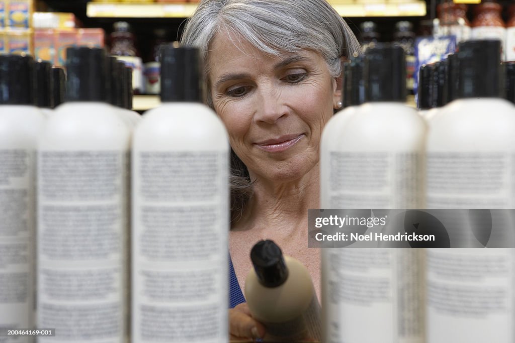 Mature woman reading shampoo label in store, close-up