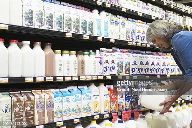 mature woman reading milk label in supermarket, side view, close-up - dairy product stock-fotos und bilder