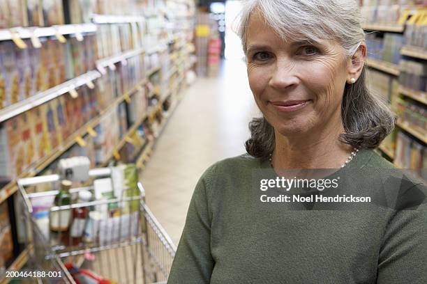 mature woman smiling in supermarket aisle, portrait, close-up - multiple same person stock pictures, royalty-free photos & images