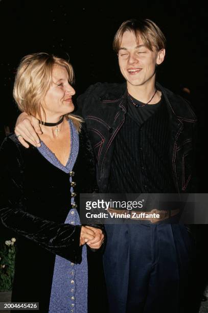 American actor Leonardo DiCaprio, wearing a black crew neck top beneath a black jacket with red stitching, and his mother, Irmelin Indenbirken, who...
